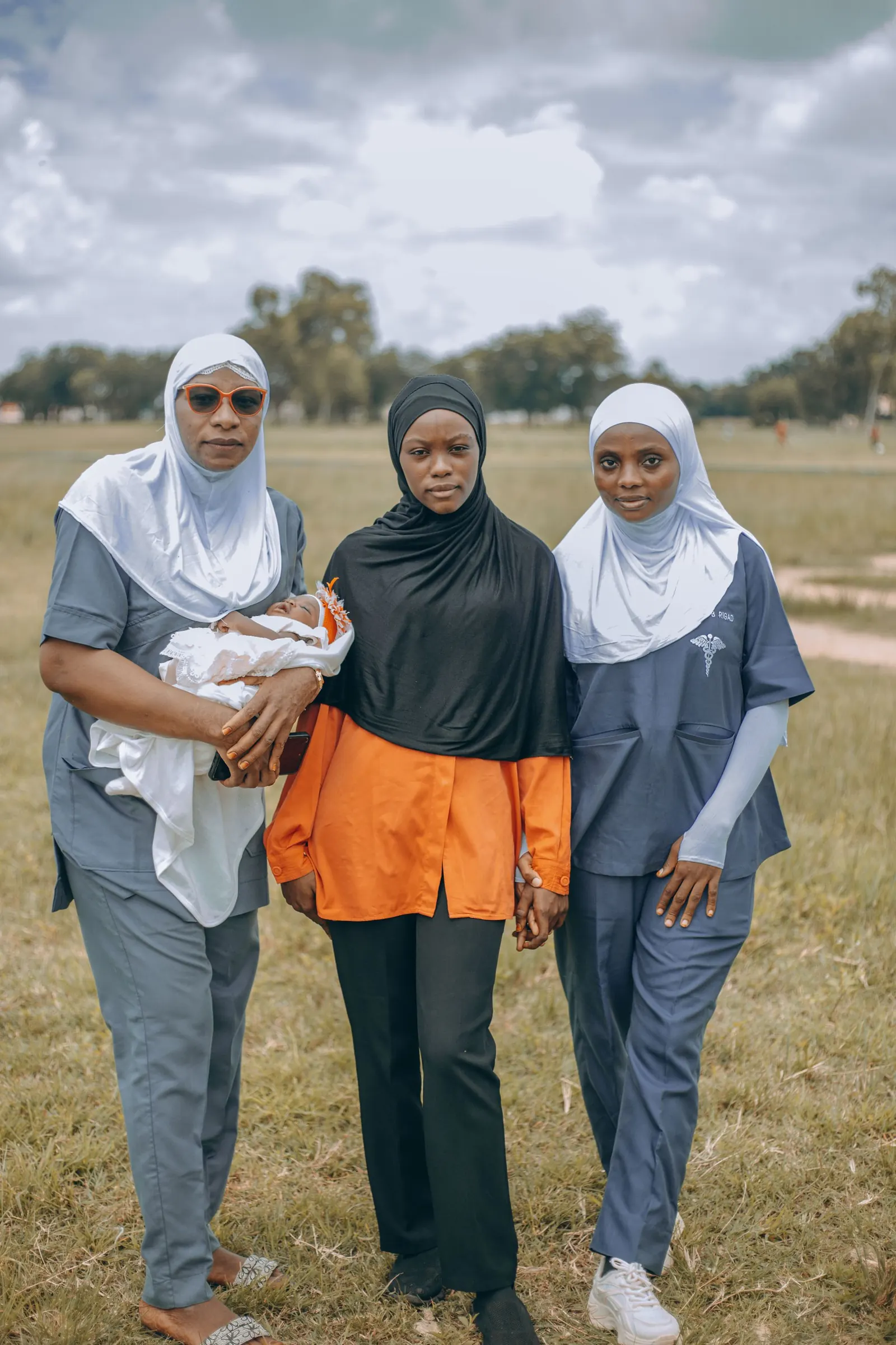 Nurses in hijabs standing with a mother holding her baby