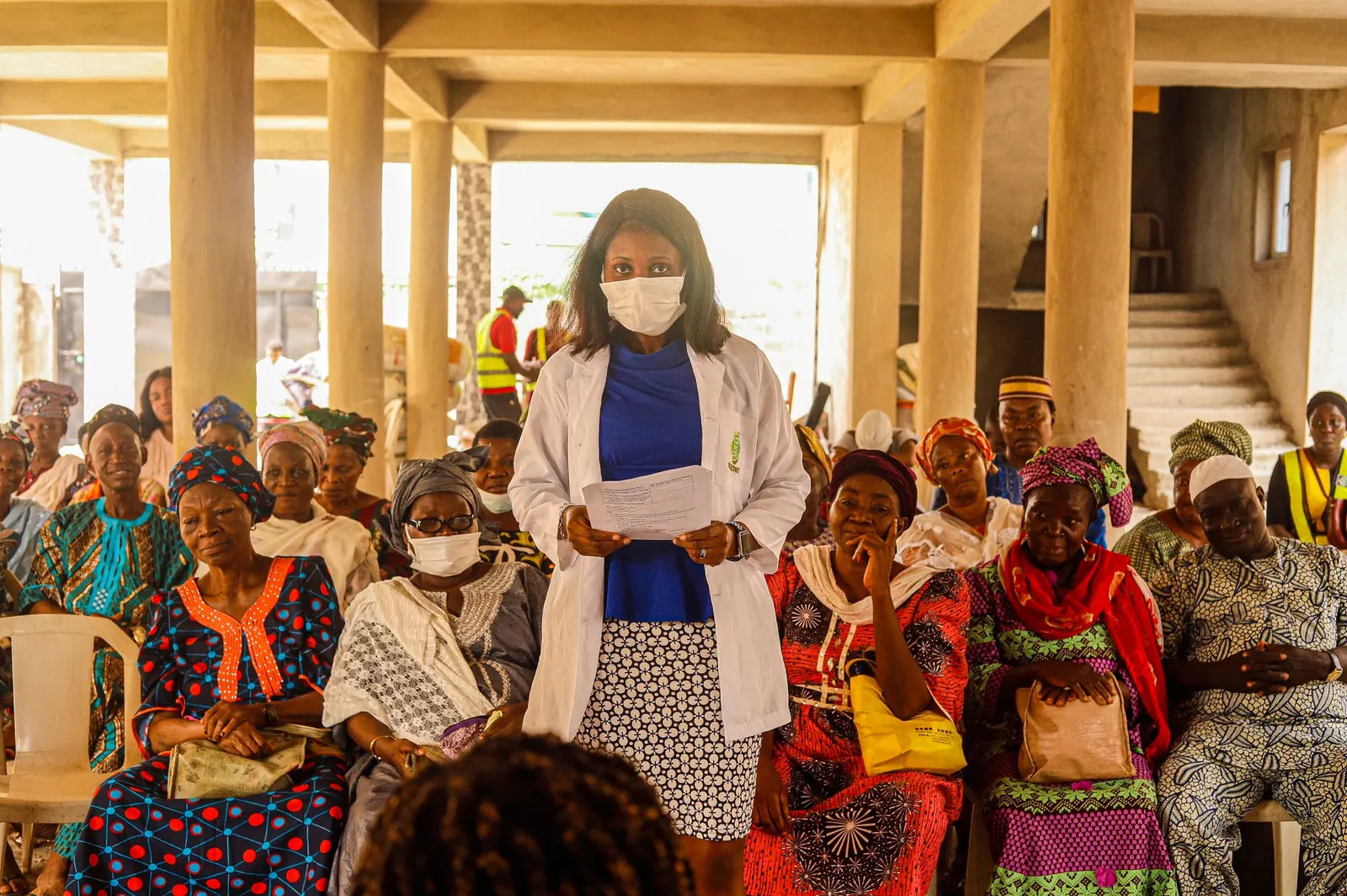 Female doctor giving a health talk to a large group of women at a community centre